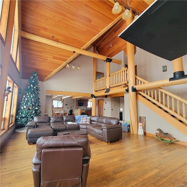 living room with light wood-style floors, wooden ceiling, high vaulted ceiling, and stairway