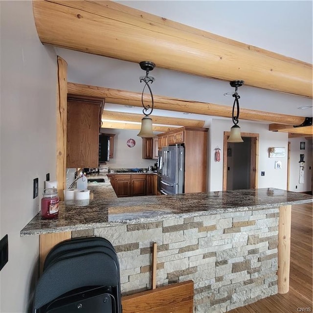 kitchen with a peninsula, high end refrigerator, brown cabinets, and pendant lighting