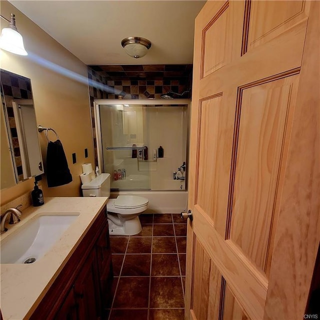 bathroom featuring toilet, enclosed tub / shower combo, vanity, and tile patterned floors