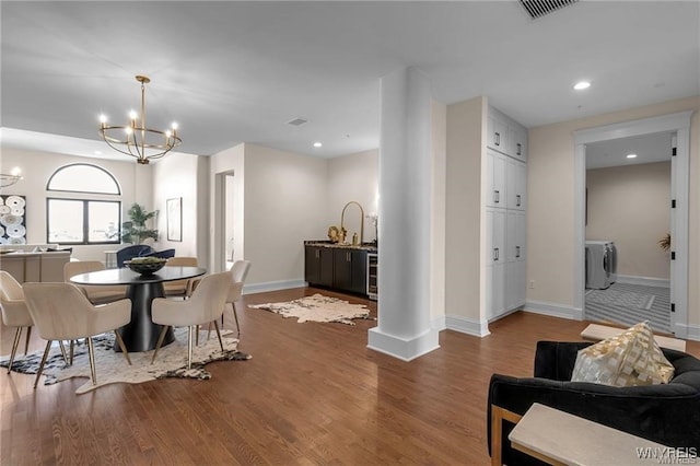 dining room featuring a notable chandelier, visible vents, wood finished floors, independent washer and dryer, and baseboards