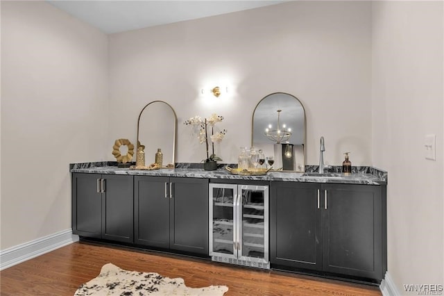 bar with a sink, beverage cooler, baseboards, and wood finished floors