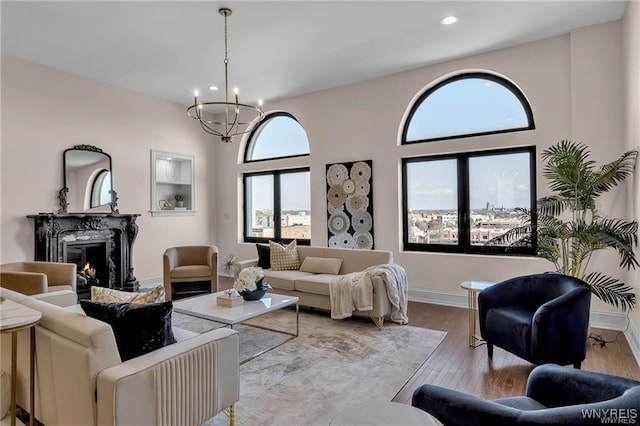 living area with a chandelier, light wood-style flooring, recessed lighting, a premium fireplace, and baseboards