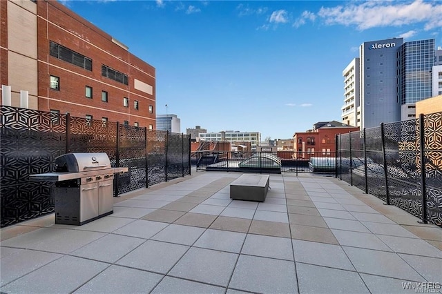 view of patio / terrace featuring a view of city, a gate, a grill, and fence