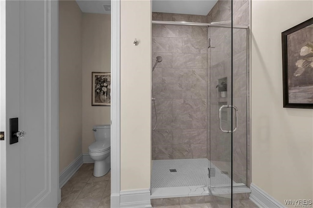 full bathroom featuring toilet, a shower stall, and baseboards