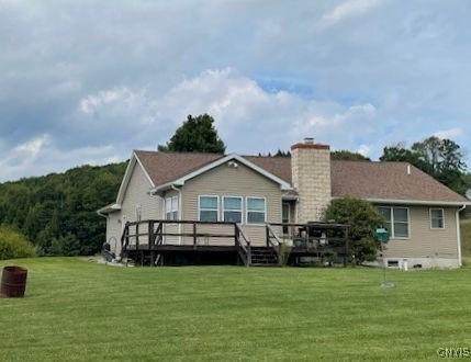 back of property with a yard, a chimney, and a wooden deck