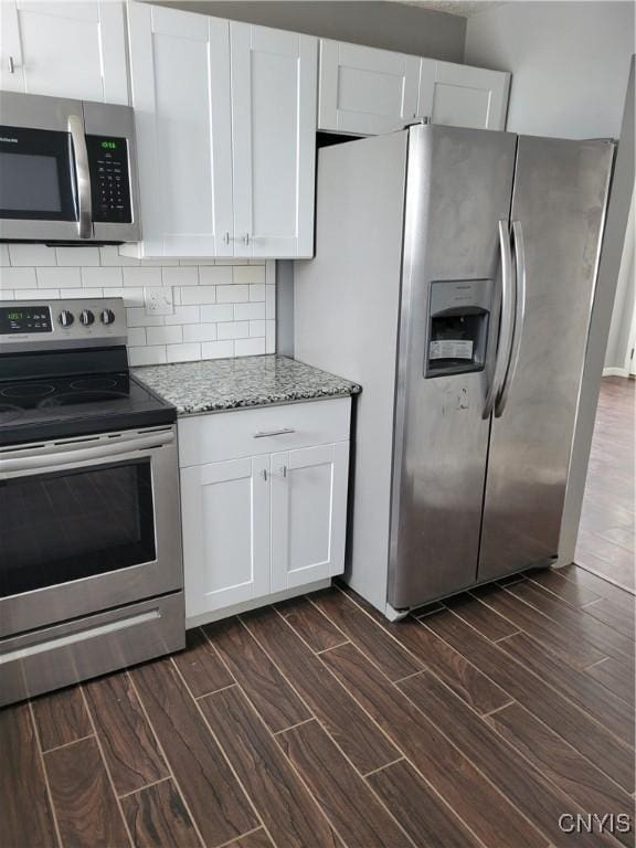 kitchen featuring appliances with stainless steel finishes, wood finish floors, white cabinetry, and tasteful backsplash