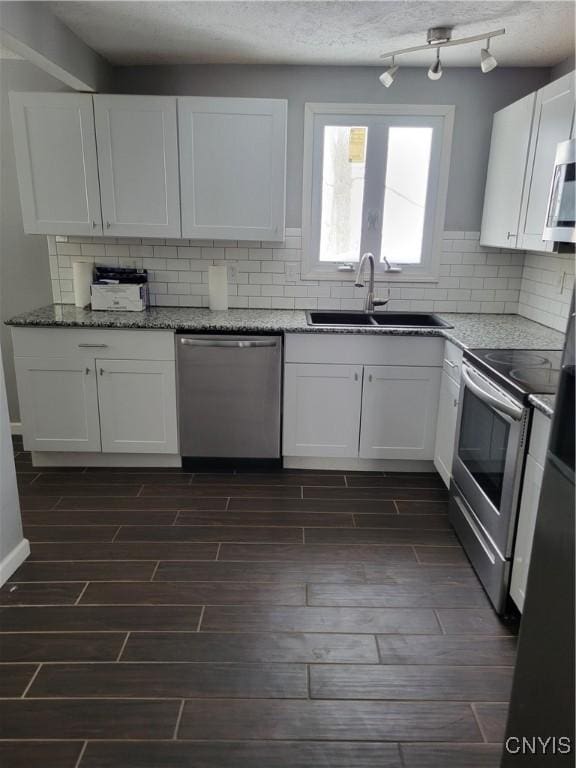 kitchen with white cabinetry, stainless steel appliances, a sink, and wood finish floors