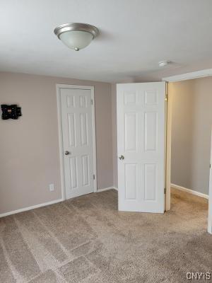 unfurnished bedroom featuring light carpet and baseboards