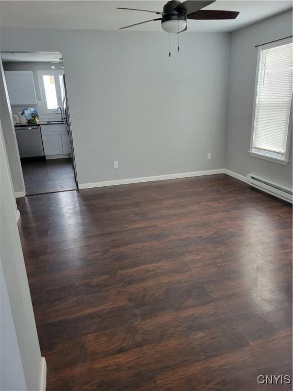 spare room featuring ceiling fan, dark wood-type flooring, a sink, baseboards, and baseboard heating