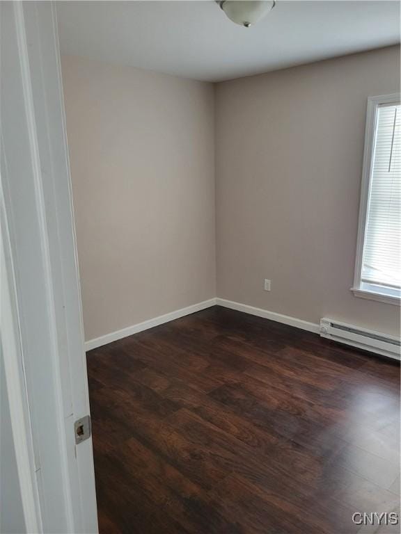 empty room featuring a wealth of natural light, dark wood-style flooring, baseboards, and a baseboard radiator