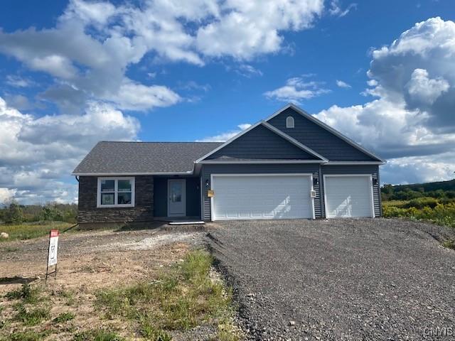 ranch-style home featuring a garage and gravel driveway