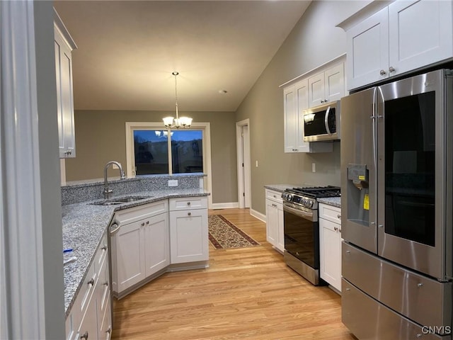 kitchen with stainless steel appliances, an inviting chandelier, white cabinetry, a sink, and light stone countertops