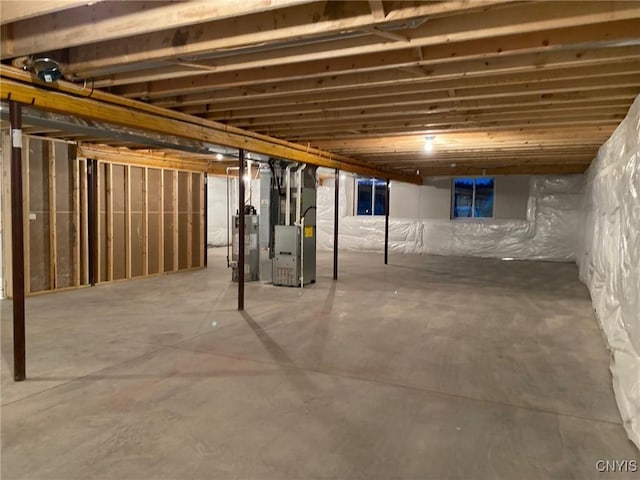 unfinished below grade area featuring heating unit and water heater