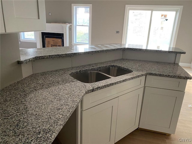 kitchen featuring light stone counters, light wood-style flooring, and white cabinetry