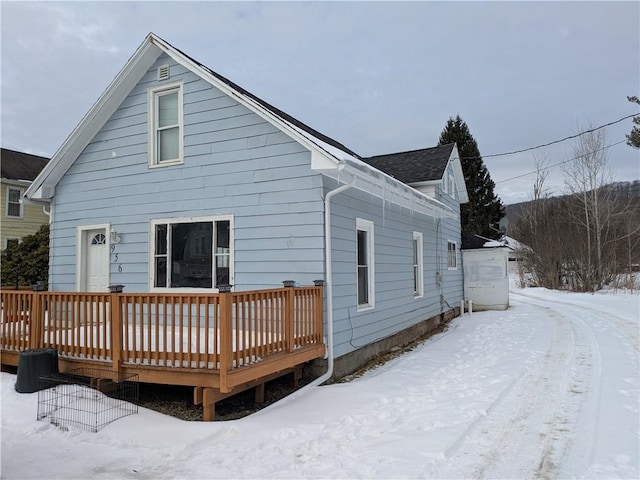 snow covered rear of property with a deck