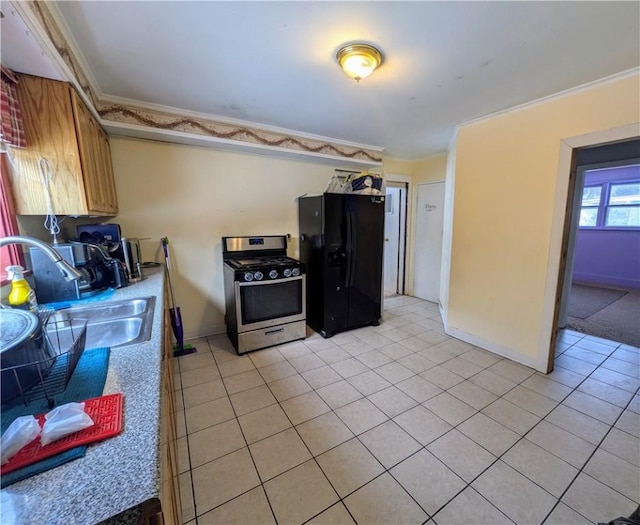 kitchen featuring a sink, ornamental molding, stainless steel range with gas cooktop, and freestanding refrigerator