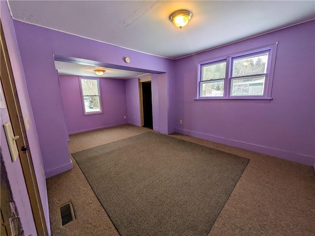 unfurnished room with carpet floors, visible vents, and baseboards