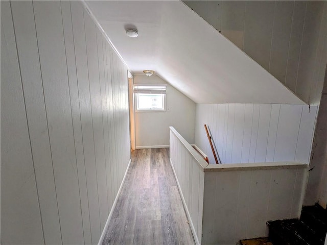 interior space with vaulted ceiling, light wood-style flooring, and wooden walls