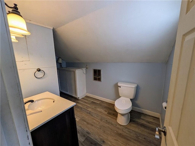 half bathroom with toilet, wood finished floors, vanity, and baseboards