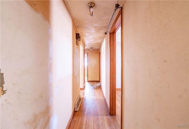 hallway featuring light wood-style flooring, visible vents, and baseboards