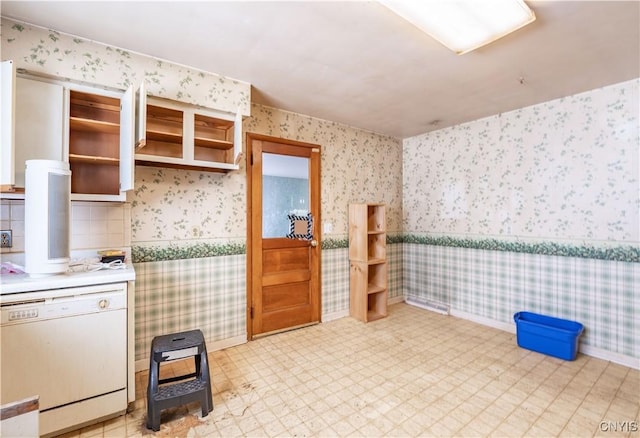 kitchen with white dishwasher, light countertops, wainscoting, light floors, and wallpapered walls