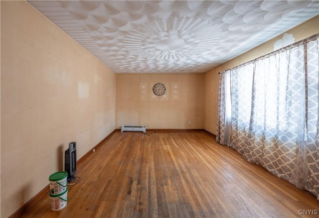 empty room featuring baseboard heating and wood finished floors