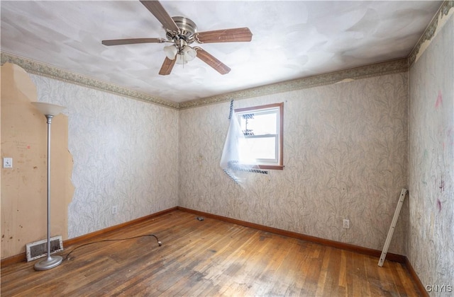 unfurnished room with ceiling fan, wood finished floors, visible vents, and baseboards