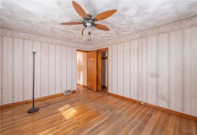 spare room with baseboards, light wood-style flooring, and wallpapered walls