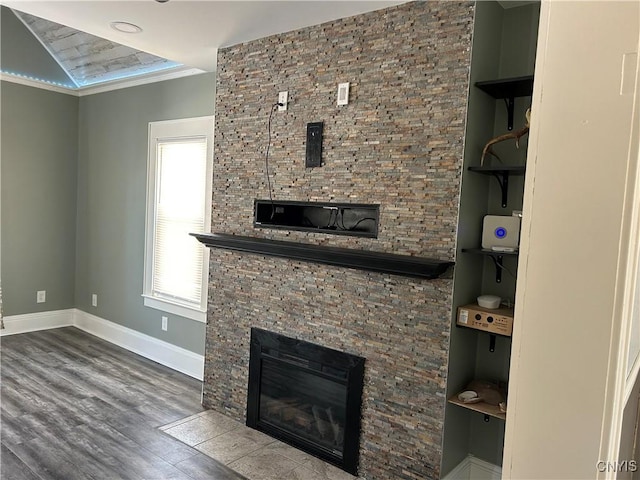 interior space featuring baseboards, wood finished floors, and a glass covered fireplace