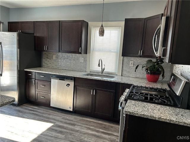 kitchen featuring appliances with stainless steel finishes, pendant lighting, a sink, and dark brown cabinets