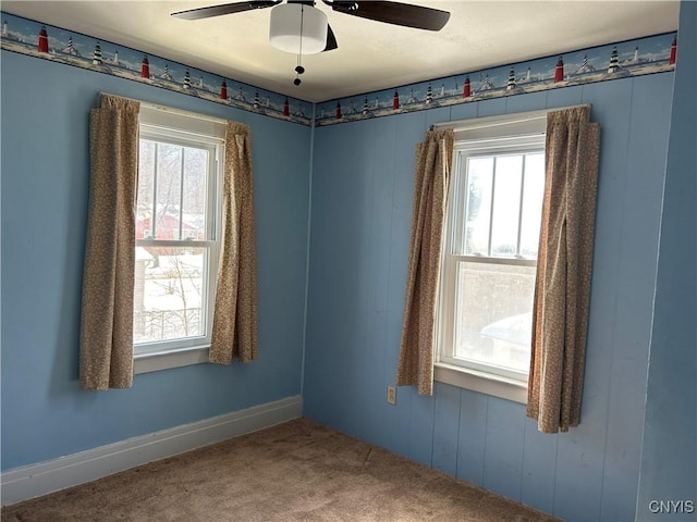 carpeted empty room with a healthy amount of sunlight, ceiling fan, and baseboards