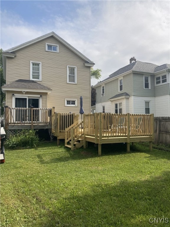 rear view of property featuring a lawn and a wooden deck