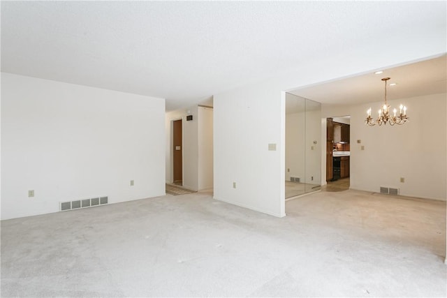 unfurnished living room with an inviting chandelier, visible vents, and light colored carpet