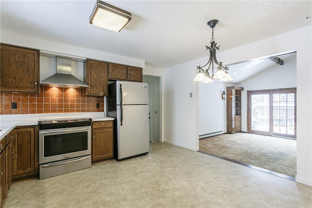 kitchen featuring pendant lighting, lofted ceiling, light countertops, appliances with stainless steel finishes, and wall chimney exhaust hood