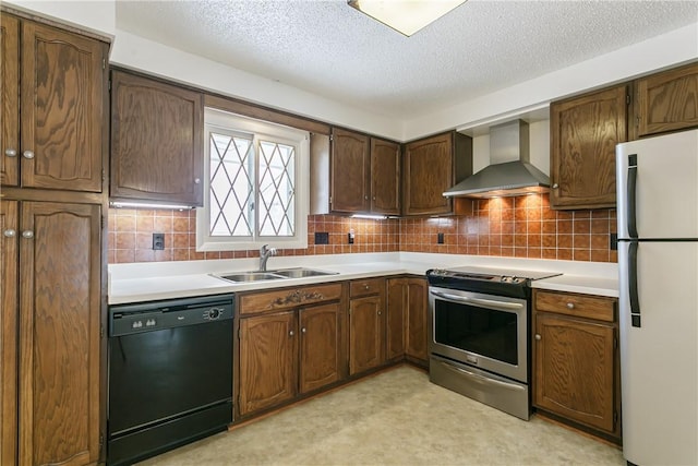 kitchen featuring freestanding refrigerator, stainless steel range with electric cooktop, a sink, dishwasher, and wall chimney exhaust hood