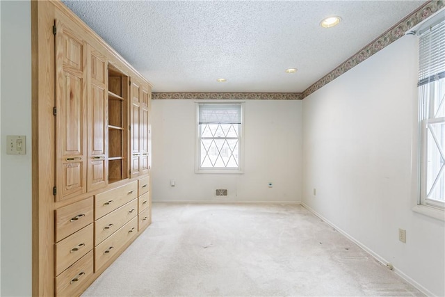 unfurnished bedroom featuring baseboards, a textured ceiling, and light colored carpet