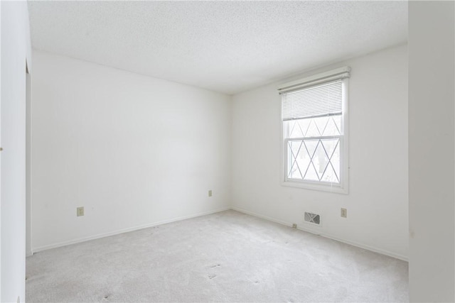 unfurnished room with visible vents, light carpet, a textured ceiling, and baseboards