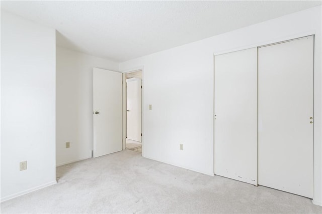 unfurnished bedroom featuring a closet and light colored carpet