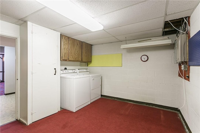 washroom featuring concrete block wall, cabinet space, dark colored carpet, and washing machine and clothes dryer