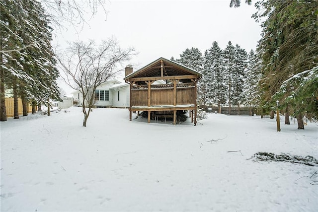 snow covered rear of property featuring a chimney