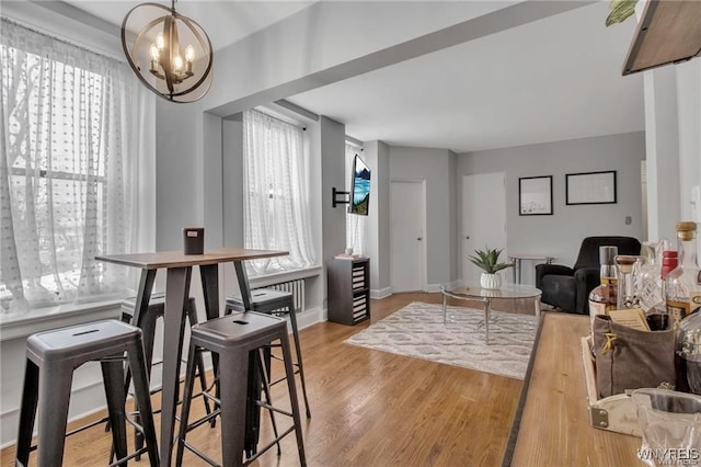 interior space featuring radiator, light wood finished floors, plenty of natural light, and an inviting chandelier