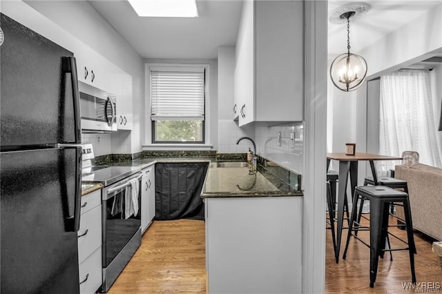 kitchen featuring white cabinets, appliances with stainless steel finishes, hanging light fixtures, light wood-type flooring, and a sink