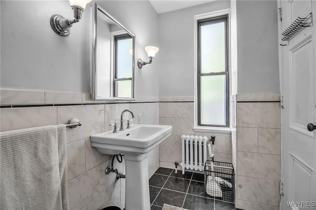 bathroom featuring radiator heating unit, tile patterned floors, tile walls, and a healthy amount of sunlight