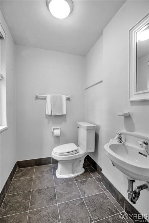 bathroom featuring toilet, baseboards, and a sink