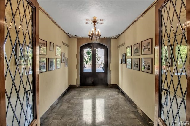 entryway with baseboards, arched walkways, ornamental molding, an inviting chandelier, and french doors