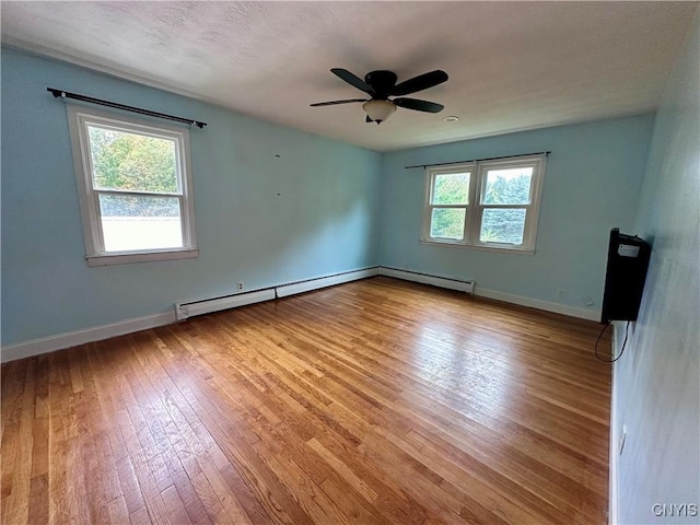 unfurnished room featuring baseboards, a baseboard heating unit, plenty of natural light, and light wood-style floors