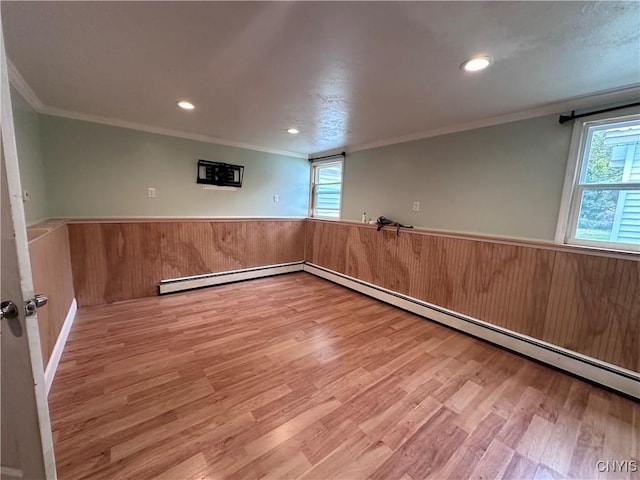 basement featuring a healthy amount of sunlight, wood finished floors, and wainscoting