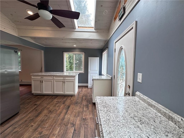 kitchen with white cabinets, baseboard heating, stainless steel refrigerator, light stone countertops, and dark wood finished floors