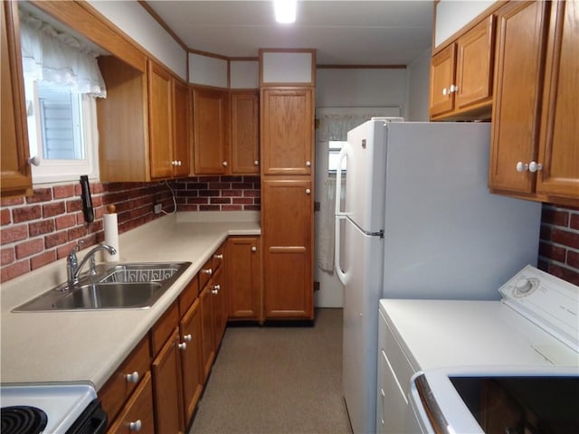 kitchen featuring brown cabinets, washer / dryer, light countertops, and a sink