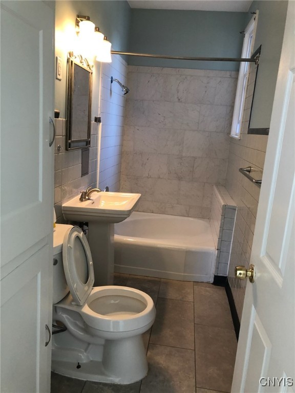 full bathroom with tile walls, toilet, shower / tub combination, and tile patterned flooring